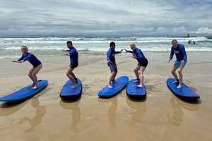 group standing on surf boards on a beach